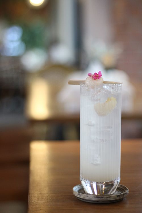 Free A refreshing lychee mocktail with floral garnish set on a wooden table in a cozy cafe. Stock Photo