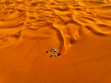 Stunning aerial photo capturing vast sand dunes and vehicles in the Sahara Desert.