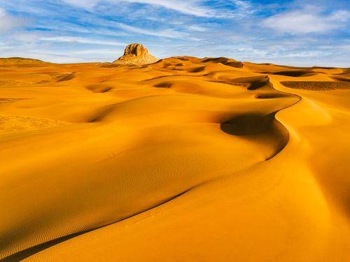 Free Captivating view of golden sand dunes in Kumtag Desert with clear blue sky and white clouds. Stock Photo