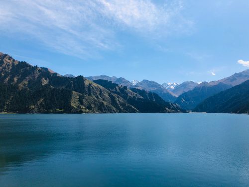 Free Breathtaking scenery of clear lake with mountainous backdrop under blue sky in Xinjiang, China. Stock Photo