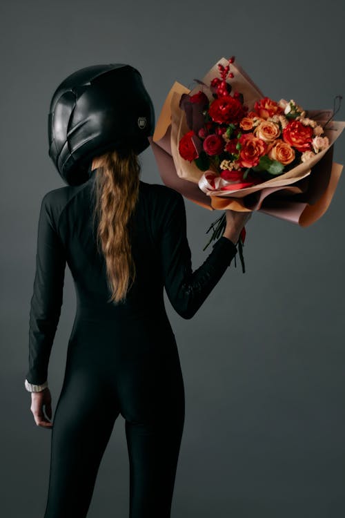 Free Woman in Black Bodysuit and helmet Holding a Bouquet Stock Photo