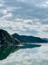 Green Mountains Beside Lake Under Cloudy Sky
