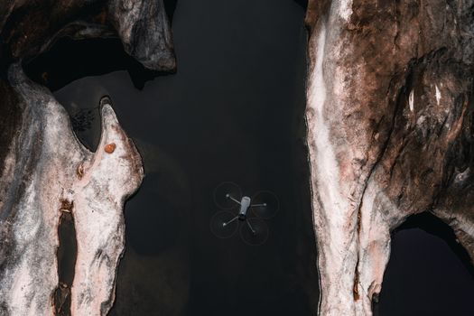 Aerial shot of a drone flying between rocky formations at a seashore in KL, India.