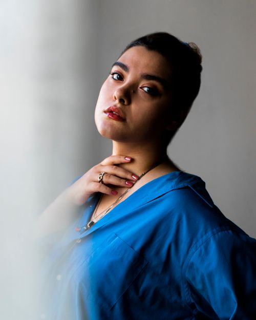 Free Elegant portrait of a woman in a blue top with soft lighting and a serene expression. Stock Photo