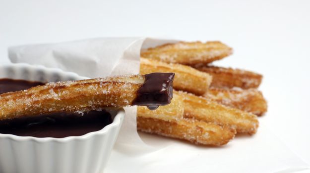 Delicious churros coated in sugar, dipped in rich chocolate sauce, perfect for dessert lovers.