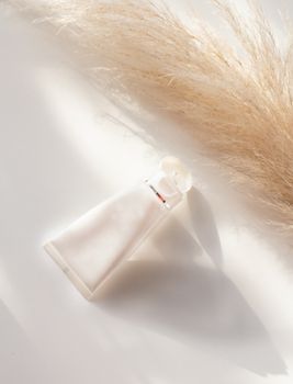 A sleek cosmetic tube on a soft background with pampas grass, perfect for branding.