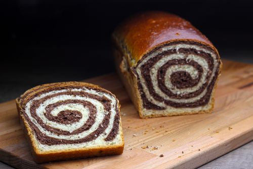 Free Close-up of a freshly baked swirl bread loaf and slice on a wooden cutting board. Stock Photo