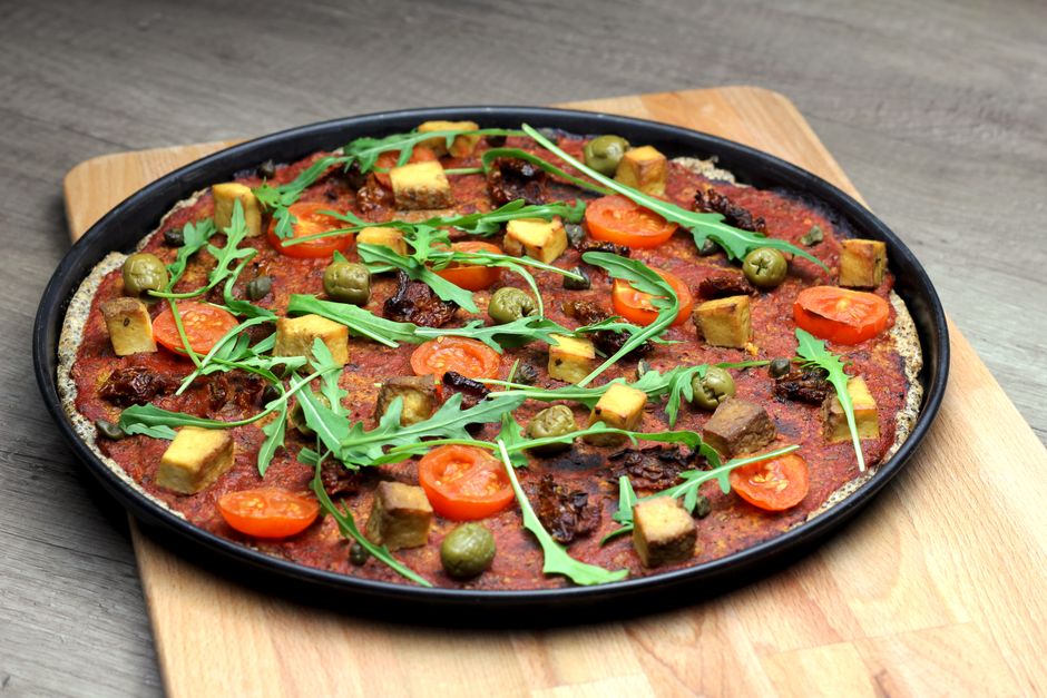 gluten-free pizza crust with tomato sauce and basil