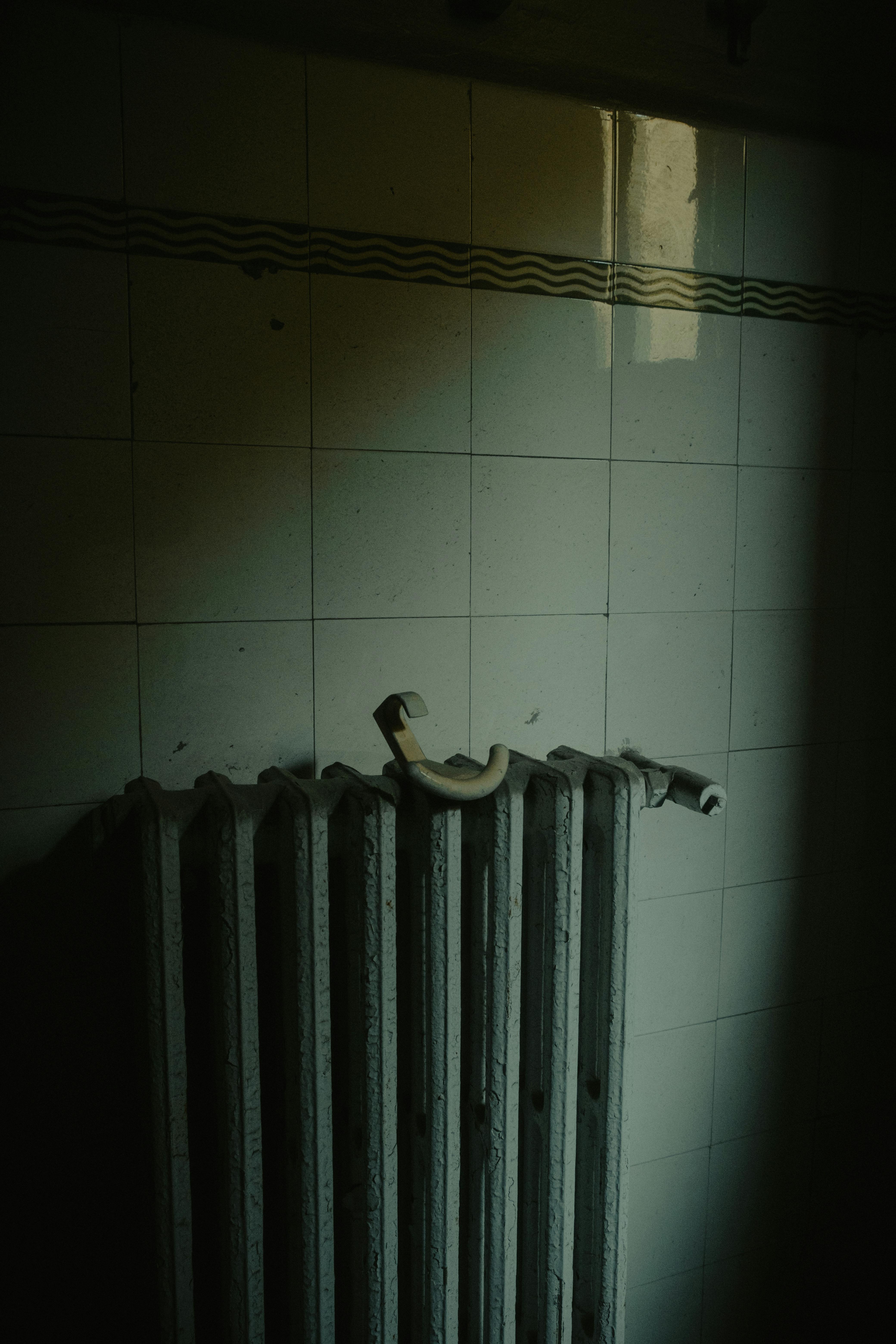 A vintage cast-iron radiator against a tiled wall in warm afternoon light.