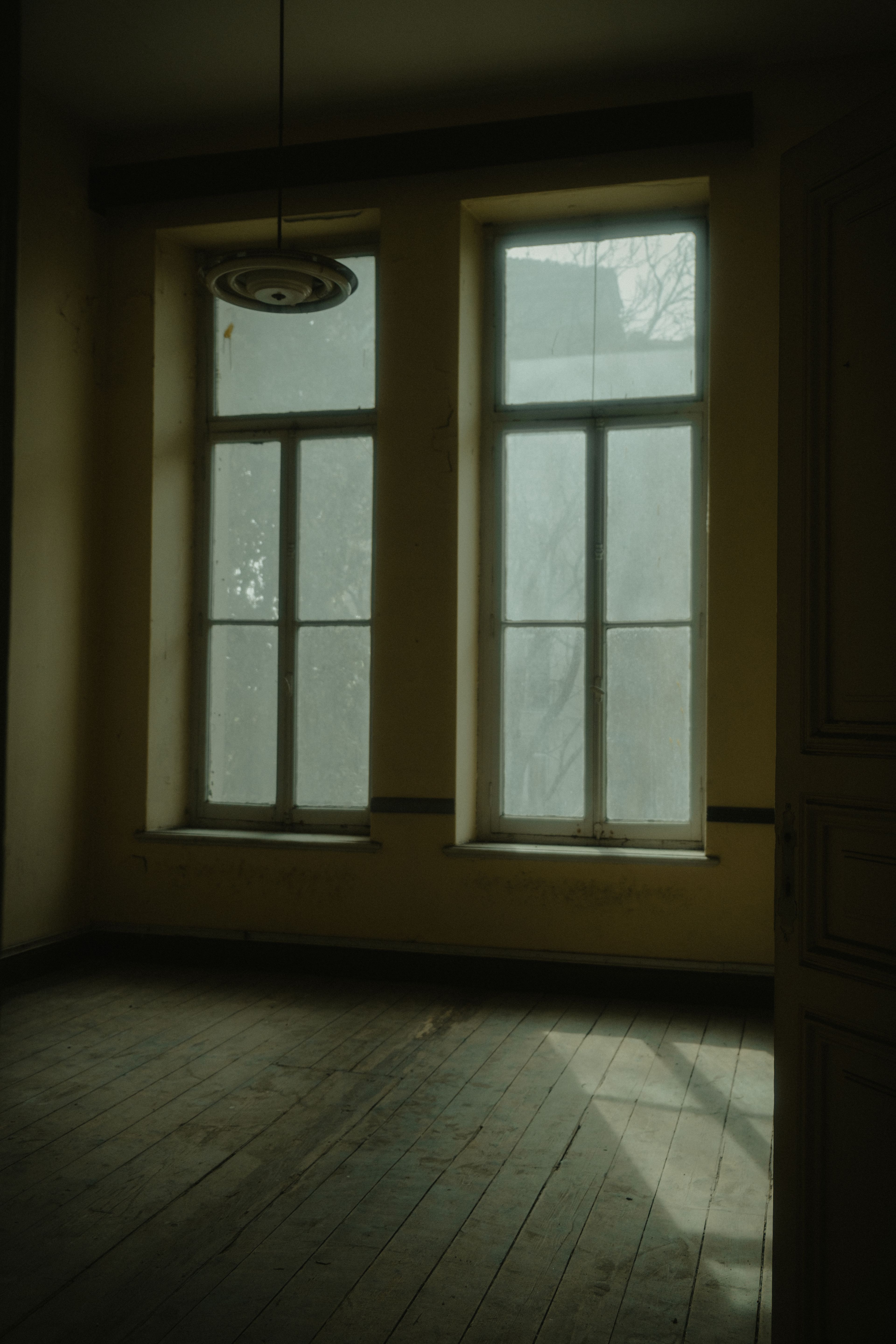 Il y a quelqu’un derrière la porte Pièce au parquet ancien, éclairée doucement par la lumière d’une fenêtre