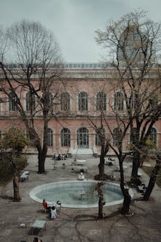 Aerial view of a historic building with a courtyard, featuring trees and people relaxing.