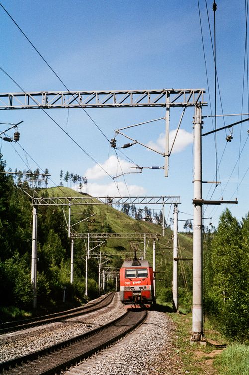 Free A train travels through lush green hills, showcasing beautiful natural scenery. Stock Photo