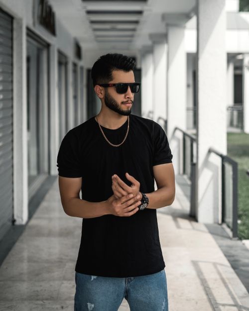 Free A confident man wearing sunglasses poses outdoors in a modern setting. Stock Photo