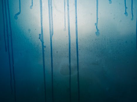 Close-up of blue paint dripping on a textured wall, creating an abstract artistic pattern.