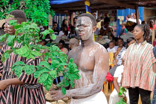 Colorful parade with traditional attire and body paint in Amedzofe, Ghana, showcasing cultural heritage.