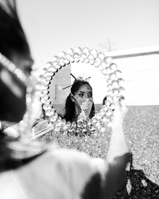 A woman gazes into an ornate mirror, capturing a stylish reflection in monochrome.