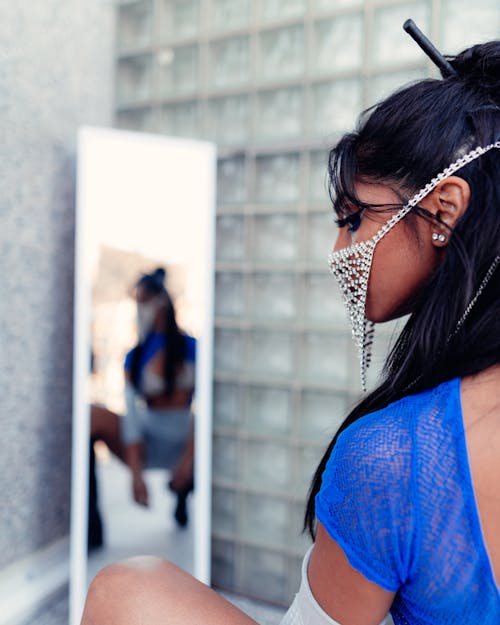 A Mirror Reflection of a Woman Wearing Facemask Dancing