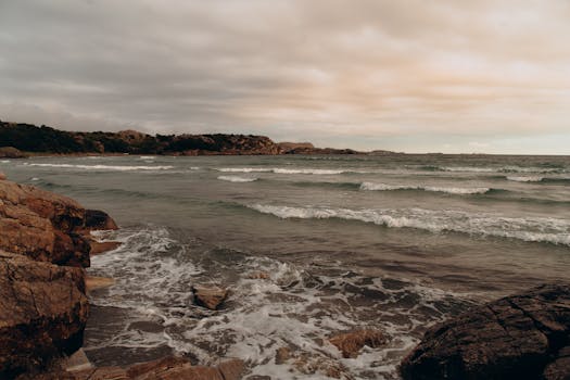 Captivating view of the Norwegian coast with dramatic waves crashing against rocky shores under a moody sky.