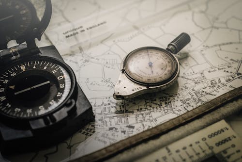 Shallow Focus Photography of Black and Silver Compasses on Top of Map