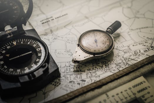 A vintage compass and navigation instrument on an old map, showcasing precision tools for exploration.