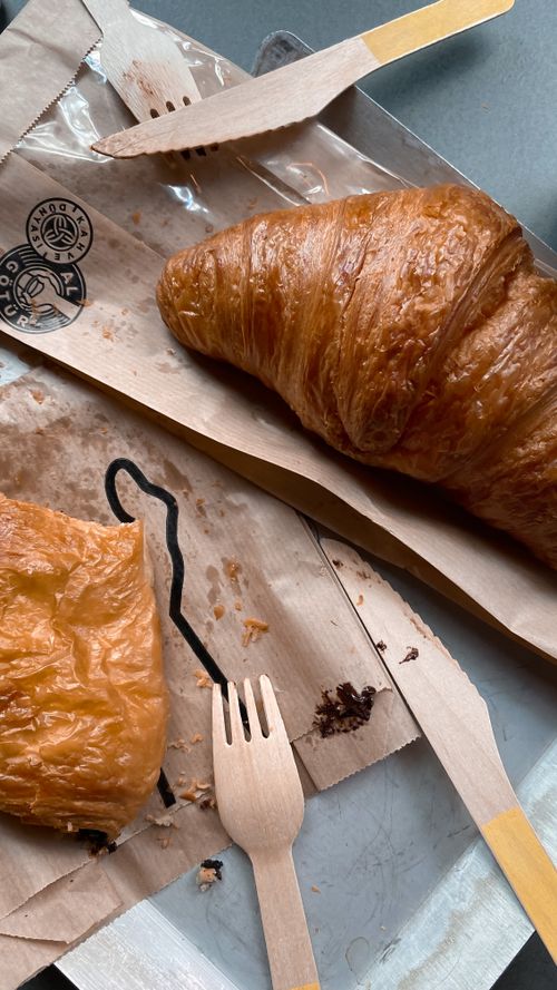 Free Delicious golden croissant served with eco-friendly wooden cutlery on parchment paper. Stock Photo