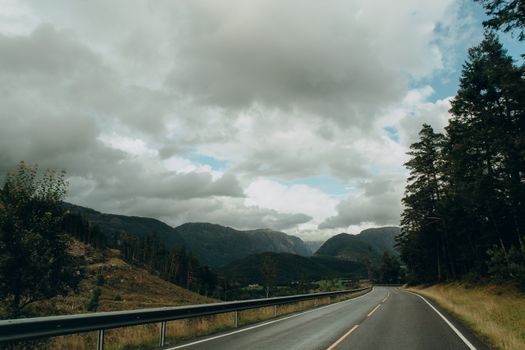 A winding road through mountains under a cloudy sky, perfect for travel or nature themes.