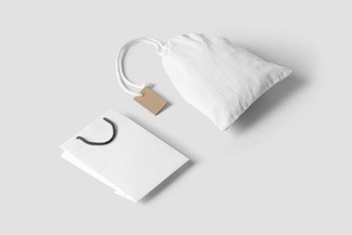 A Paper Bag and a Pouch Bag on White Surface