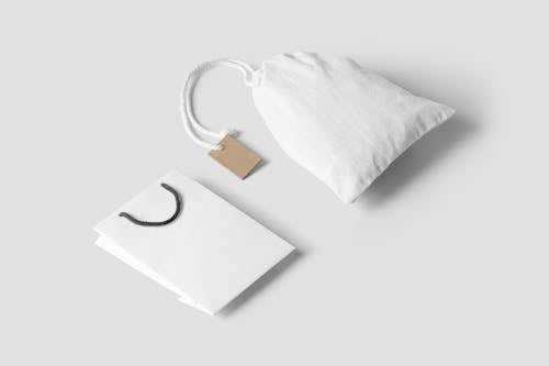 A Paper Bag and a Pouch Bag on White Surface