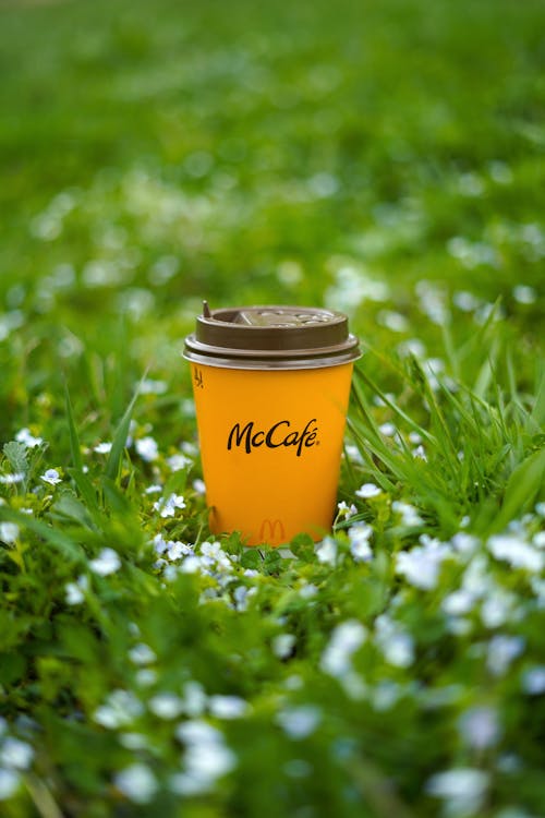 Close-Up Shot of a Yellow Paper Cup on Green Grass