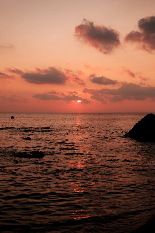 Silhouette of a Rock on Ocean during Sunset