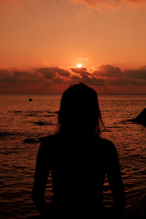 Silhouette of Woman by Sea at Sunset