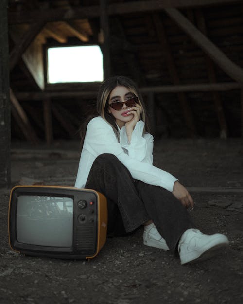 A Woman Sitting beside a Vintage Television