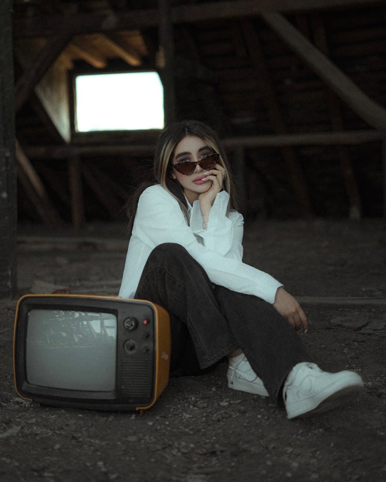 A Woman Sitting Beside A Vintage Television