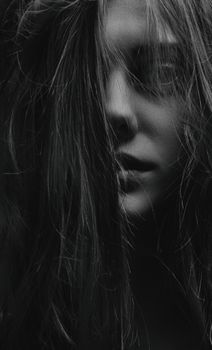Artistic close-up black and white portrait of a woman with hair covering face.