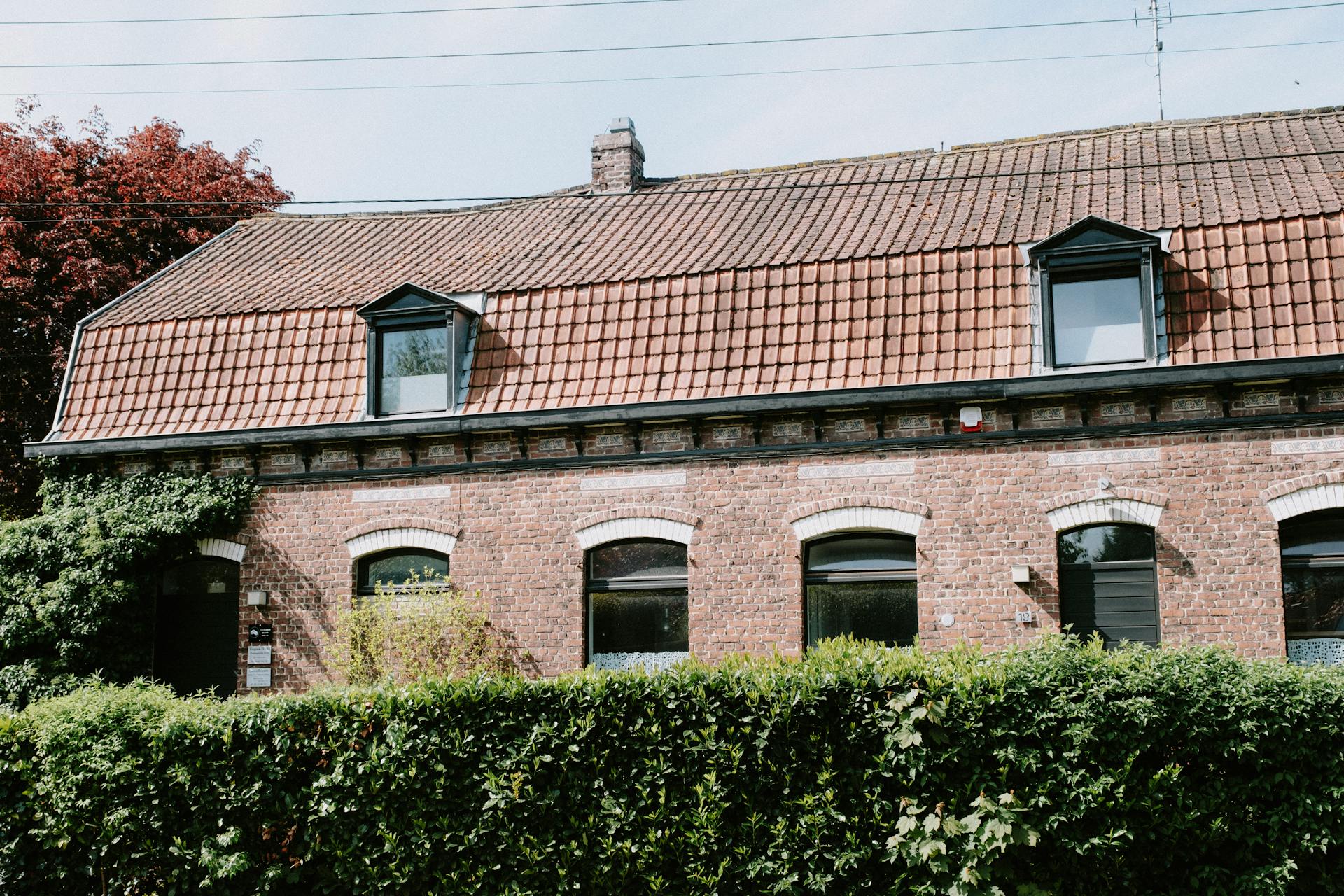 Lovely brick house with dormer windows and ivy on facade in Lille, France. Captures traditional architecture.