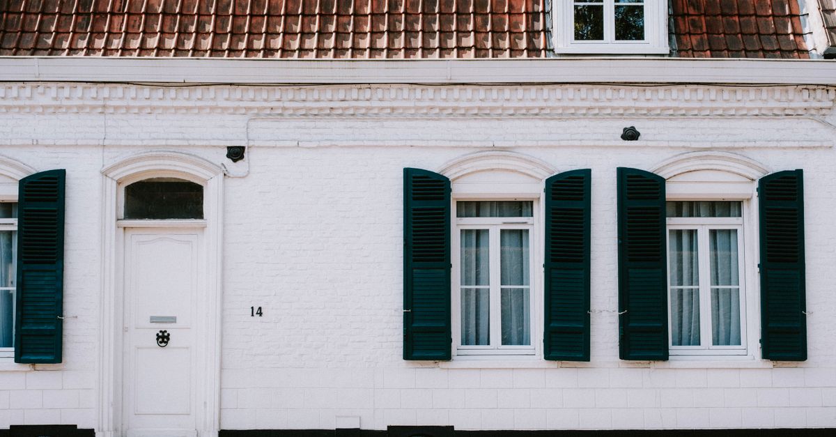 Charmante façade blanche avec volets bleus sur un cottage de style européen. Idéal pour du contenu architectural.