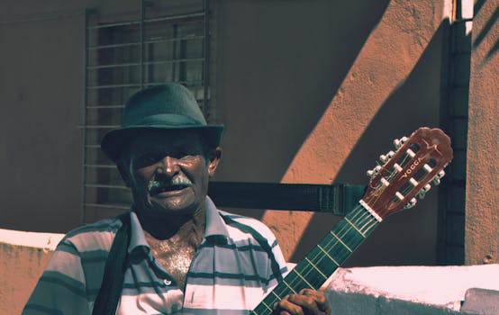 一位戴着帽子的老人在户外弹着吉他，沉浸在音乐与怀旧之中