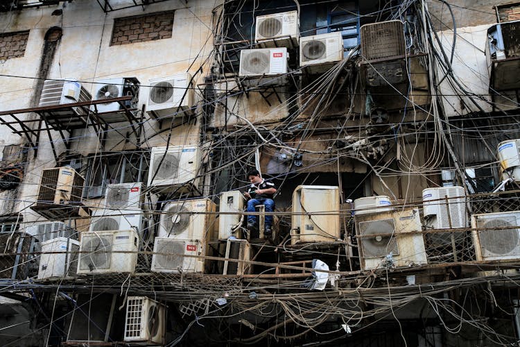 Man Working With Tangled Cables And Air Conditioning On Building Wall