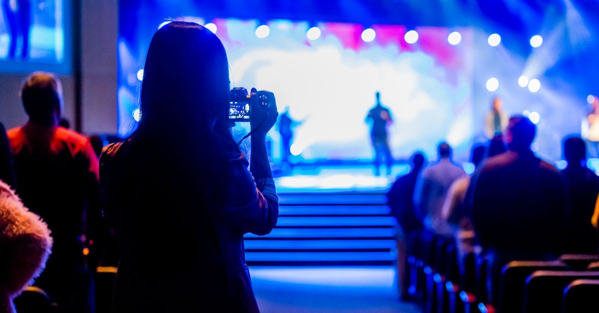 Audience capturing live concert moments with a smartphone from the back view.