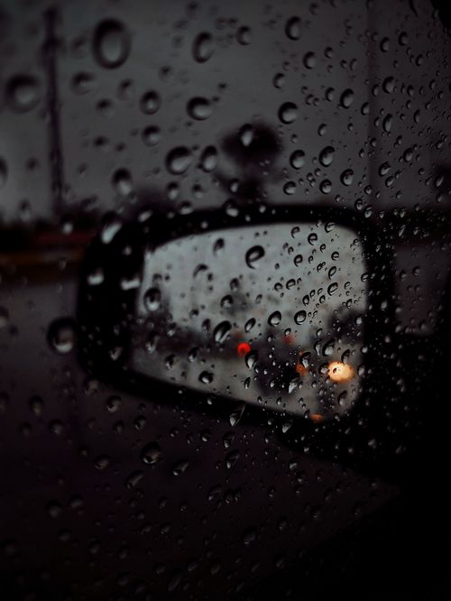 Free Moody shot of raindrops on a car window reflecting blurred city lights at night. Stock Photo