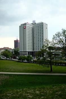 Contemporary hotel buildings surrounded by urban park area on a cloudy day.