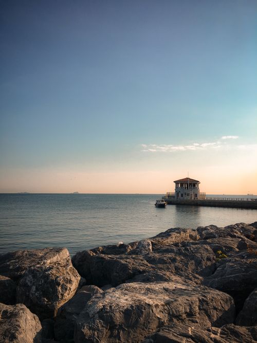 Free Beautiful sunset view of a pier with rocky shore in İstanbul, Turkey. Ideal for travel and nature themes. Stock Photo