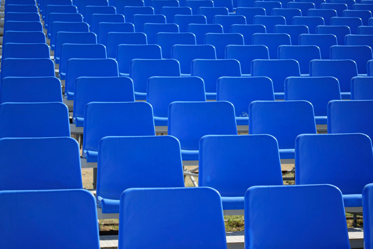 rows of empty blue stadium seats arranged in an outdoor setting