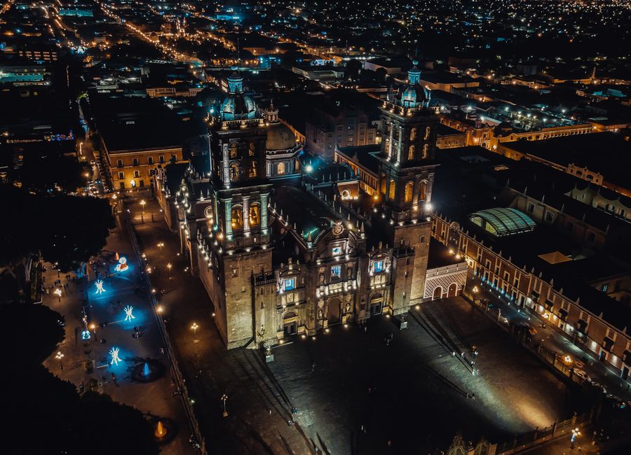Stunning aerial nighttime view of Puebla Cathedral illuminated amidst city lights in Puebla, Mexico.