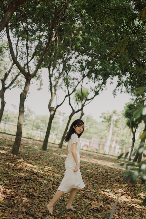 Free Young woman walking barefoot in a serene forest, embracing nature. Stock Photo