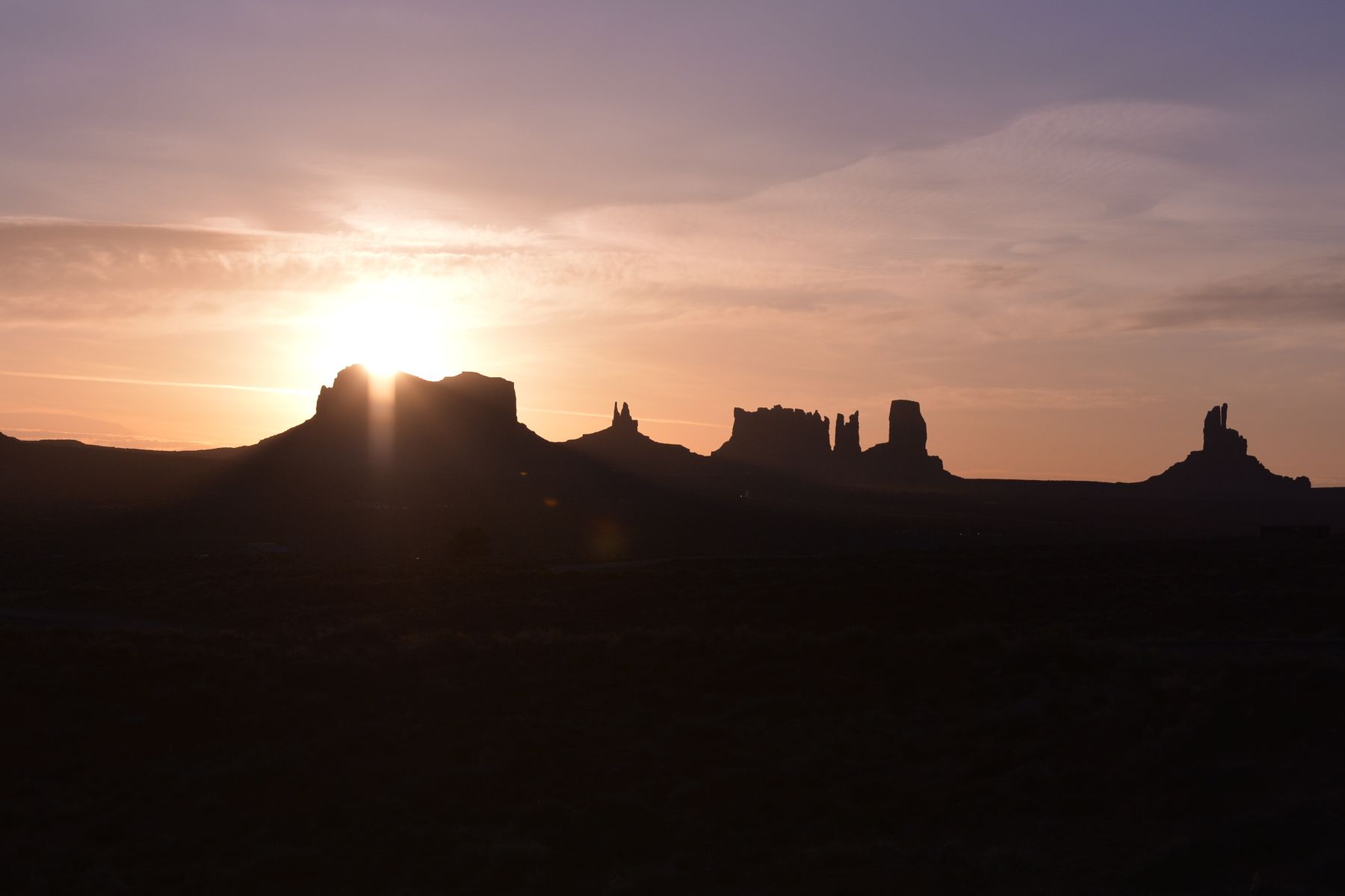The buttes of Monument Valley in silhouette against the setting sun