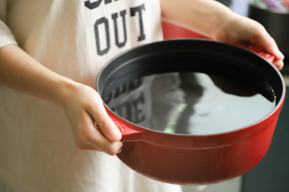 Free Person Holding Red Pot Filled with Water Stock Photo