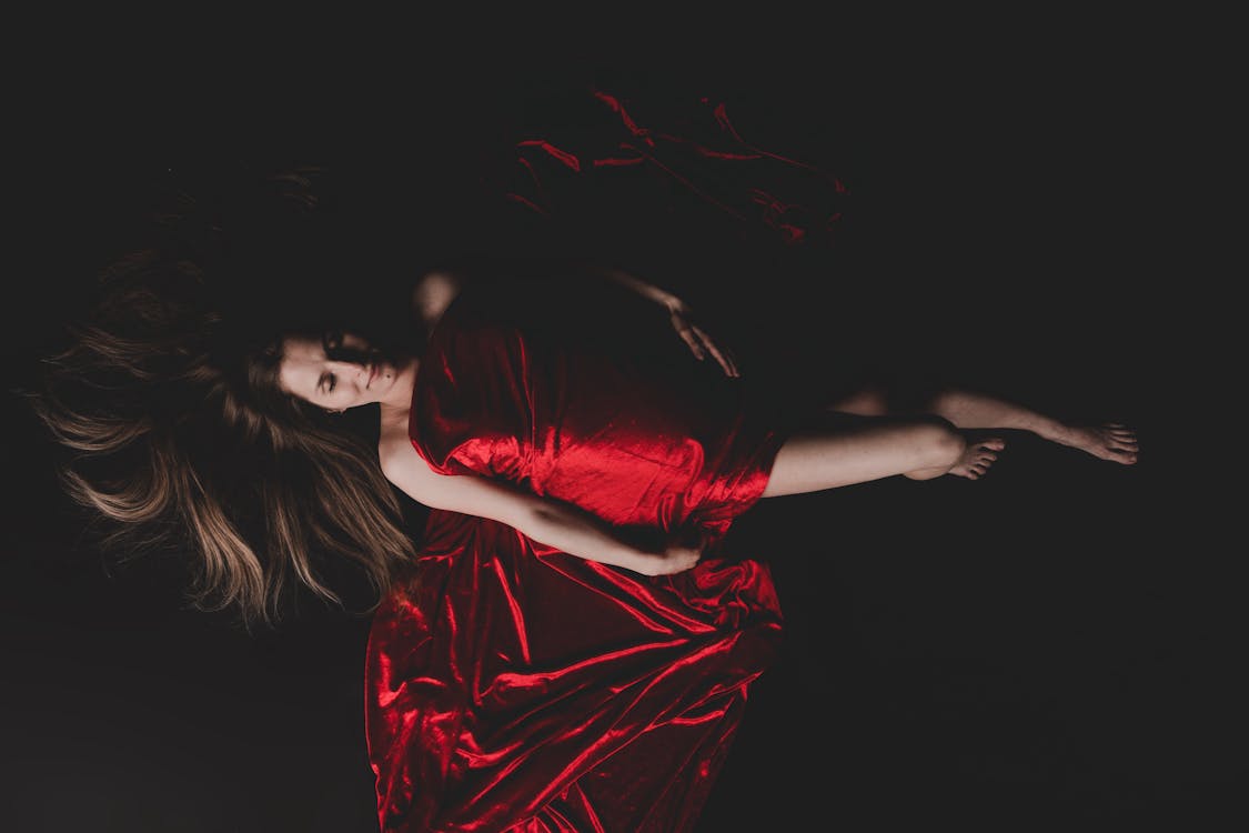 Woman Covered with Red Fabric while Lying on the Ground