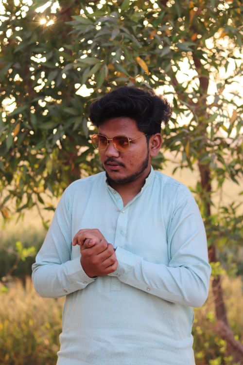 Free Stylish man in sunglasses and light blue shirt posing outdoors, showcasing modern fashion. Stock Photo