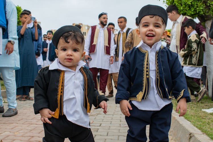 Cute Little Toddlers Wearing Traditional Clothing While Smiling At The Camera